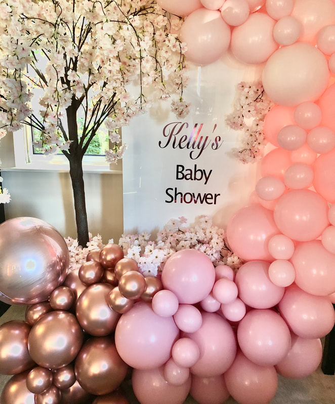 Baby shower in Cheshire with personalised backdrop with rose gold and pink balloon garland and pink blossom tree. .