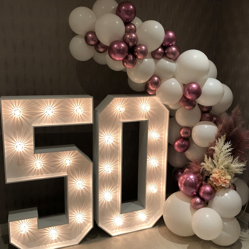 50th Birthday party in Cheshire with 4ft LED 50 numbers and balloon garland in which and pink chrome with flowers